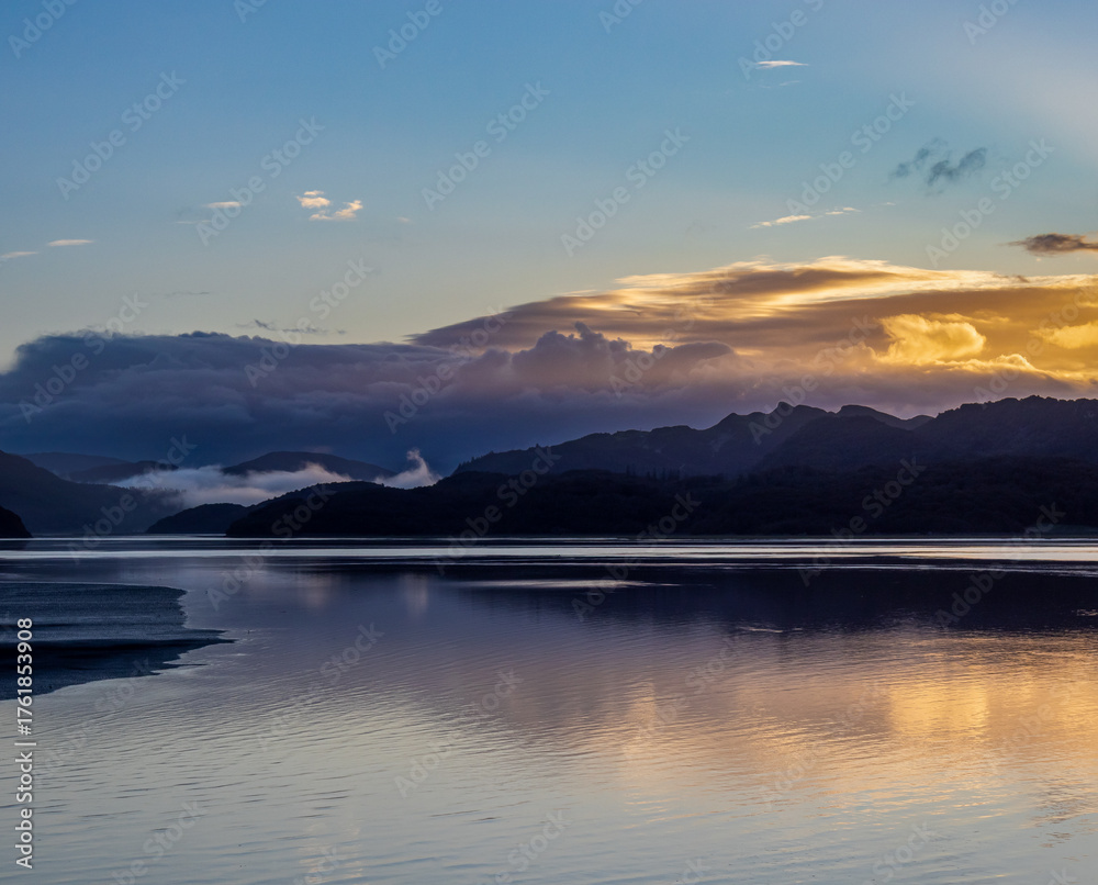 Fototapeta premium Morning light and low mist over the Mawddach Estuary with reflections on calm water