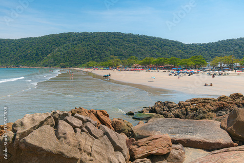 Guaiuba Beach, Guaruja SP, Brazil. Sunny day over the small bay with tranquil sea. Image of leisure and tourism on the Sao Paulo coast. Hills covered in Mata Atlantica vegetation frame the view.