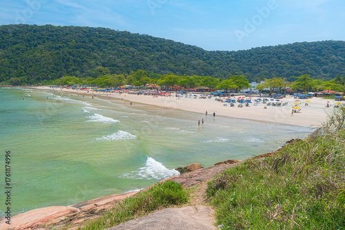 Guaiuba Beach, Guaruja SP, Brazil. Sunny day over the small bay with tranquil sea. Image of leisure and tourism on the Sao Paulo coast. Hills covered in Mata Atlantica vegetation frame the view.