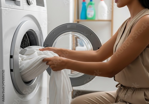 Woman loading white sheets into washing machine laundry