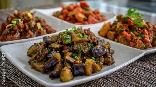 Assortment of savory dishes eggplant, chickpeas, potatoes, and a dark, shredded meat, atop white plates