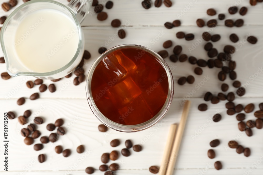Fototapeta premium Tasty iced coffee, milk and beans on white wooden table, flat lay