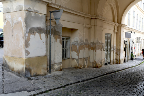Traces d'humidité et auréoles sur un immeuble ancien dans une rue pavée