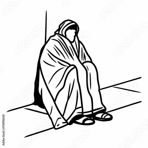 Man sitting on ground wrapped in blanket looking down in sadness  