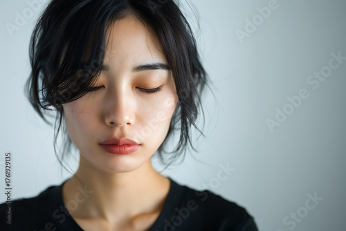 悲しみを感じながら目を閉じる日本人女性のポートレート（静かな涙と光）