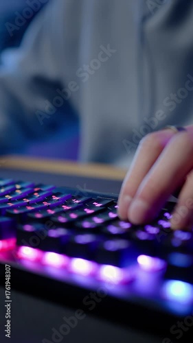 Computer keyboard with colorful lights and hands of a gamer streamer playing online video game