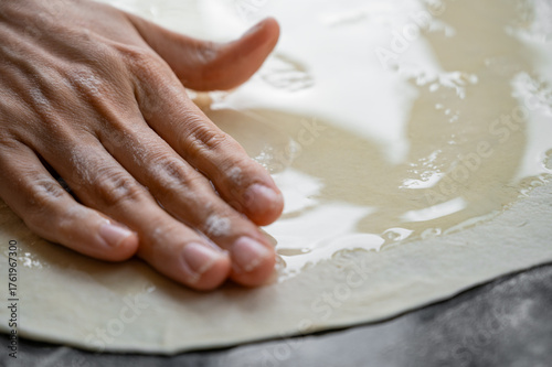 Spreading butter onto dough for puff pastry preparation. Close-up of a baking process demonstrating traditional pastry technique and culinary skill.