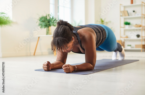 Canvastavla Young plus size African American woman doing low forearm plank exercise for abdominal muscles