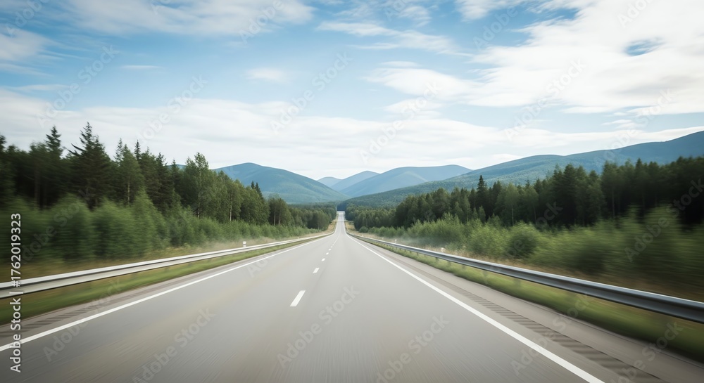 Fototapeta premium Straight road through forest with mountains in distance