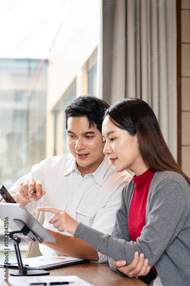Fototapeta premium Confident mature business professional man talking to younger female colleague at office table, speaking, gesturing, teaching, explaining work tasks. Elder mentor training intern.