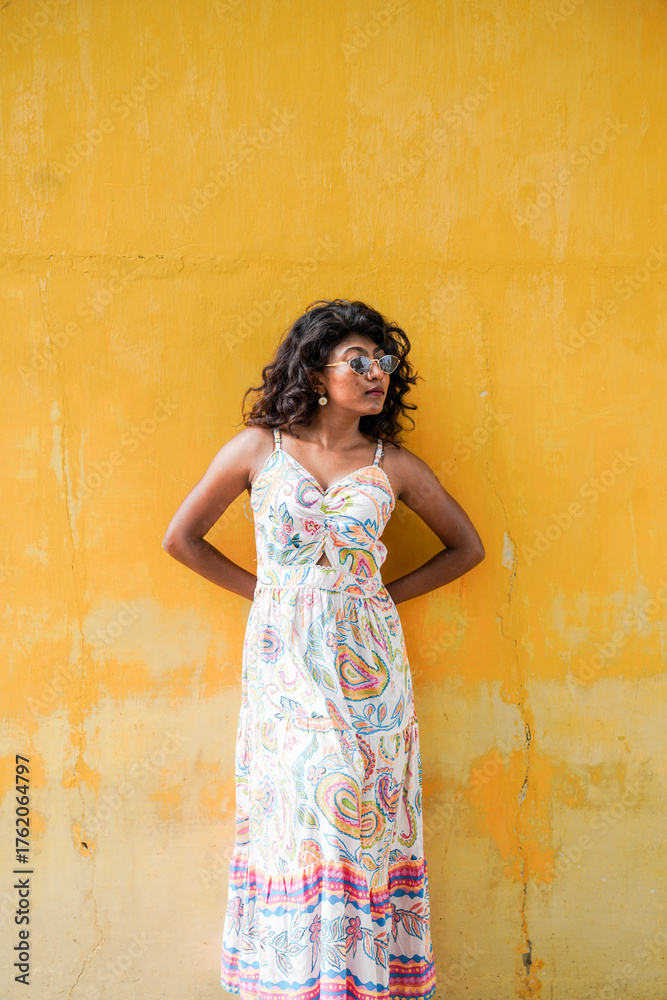 Fototapeta premium A woman in a white dress stands in front of a yellow wall