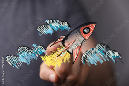 Obraz na płótnie A person's hand holding a digitally drawn rocket, symbolizing new beginnings, launching ideas, and entrepreneurial spirit