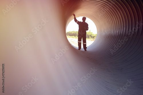 Male engineers work inside a large steel pipe. Workers build pipelines to transport oil, natural gas and fuels in industrial plants.	