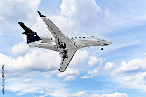 Private business plane flying under blue sky with white clouds