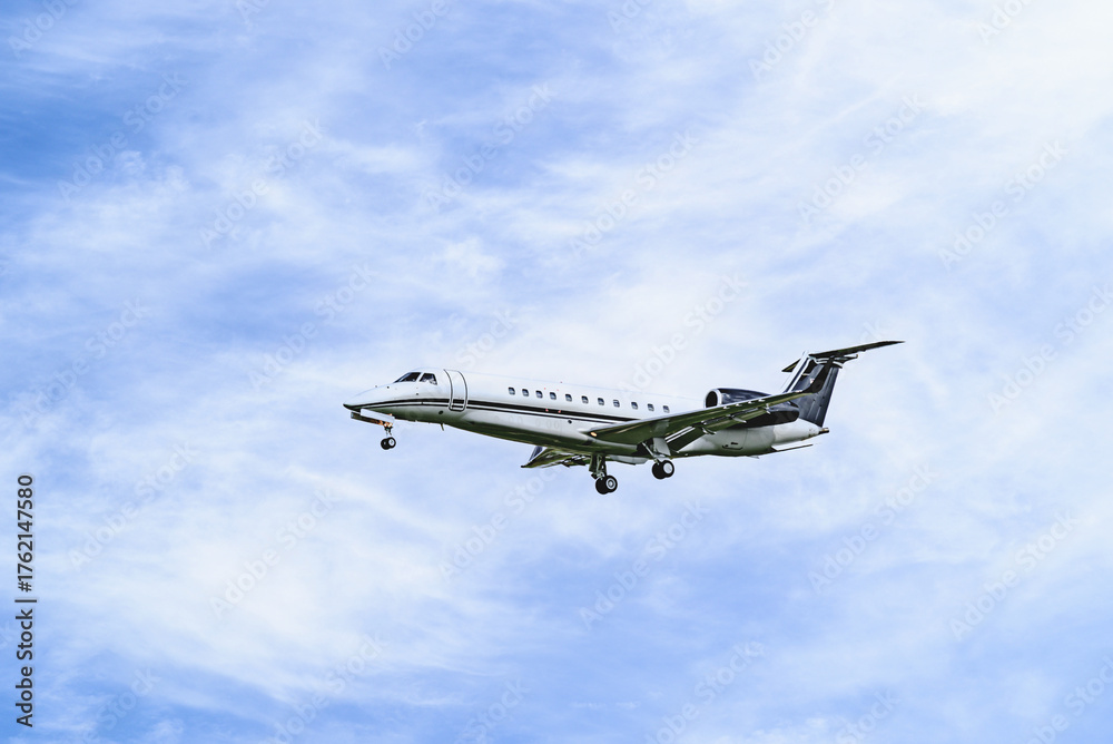 Obraz premium Private business plane flying under blue sky with white clouds