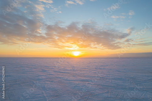 Fototapeta Naklejka Na Ścianę i Meble -  Beautiful winter sunset over a vast frozen and snow-covered plain.