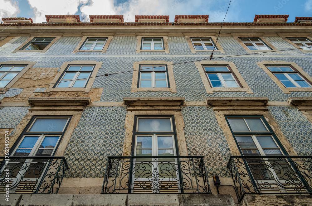 Obraz premium Weathered tiled façade of an old building in Lisbon, Portugal, showing ornamental ceramic patterns and signs of age and decay