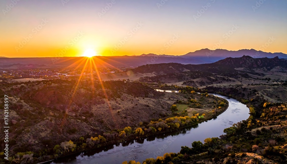 Obraz premium An aerial perspective captures a river snaking through a valley, lit by a vibrant sunset, creating a serene landscape