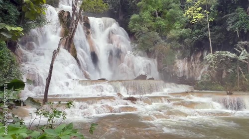 waterfall cascading through lush tropical jungle, surrounded by mist and greenery. The powerful flow of water creates a tranquil and awe-inspiring natural scene in untouched paradise