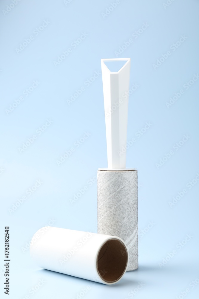 Obraz premium Lint roller with used sticky tape and new adhesive roll on light blue background
