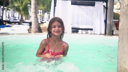Six year old girl enjoying tropical vacation at resort pool