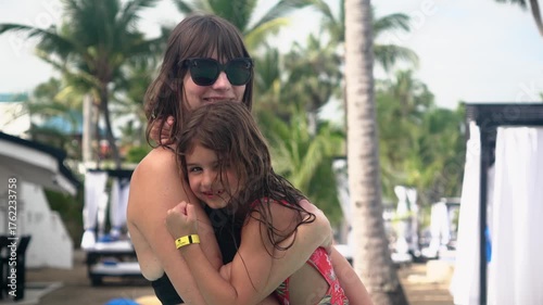 Mother and daughter smiling together in a resort pool on tropical vacation