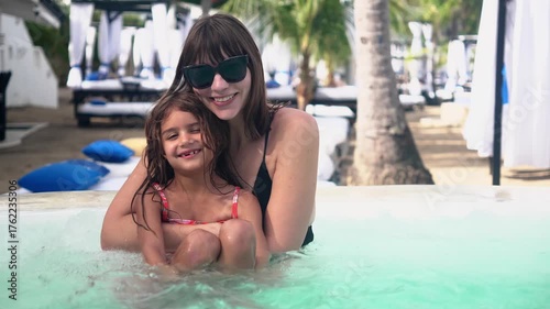 Mother and daughter smiling together in a resort pool 