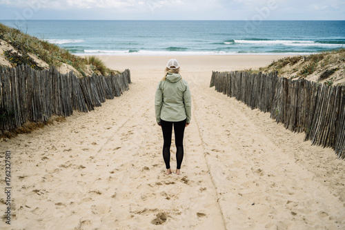 Blonde Frau mit Jacke am Strand in Frankreich bei herbstlichen Wetter