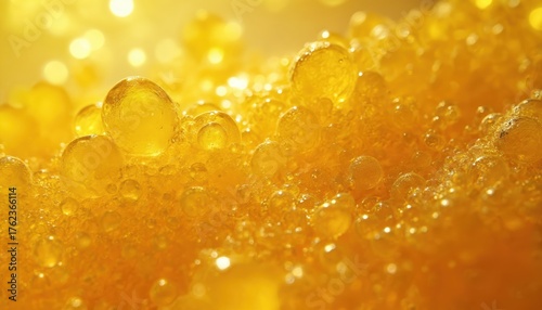 Golden yellow cannabis wax texture with many small bubbles, droplets. Marijuana shatter resin concentrate shows viscous liquid look. Macro closeup shot with rich detail, warm golden bright light.