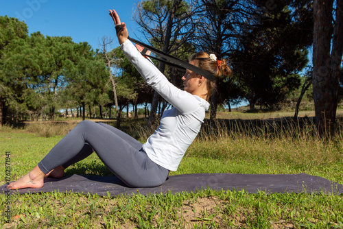 Woman exercising outdoors with resistance band on yoga mat
