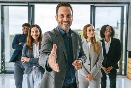 Foto Business leader extending hand to diverse professional team