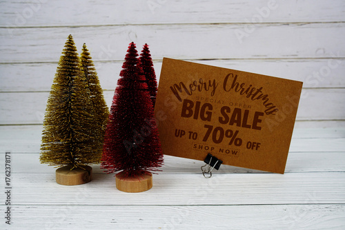 Festive display with small decorative Christmas trees with "Special Offer Merry Christmas Big Sale up to 70% off, Promotion Holiday Sale Event