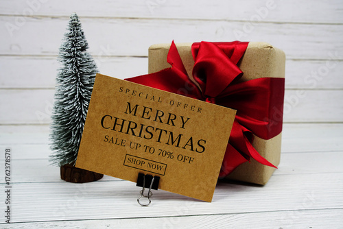 Festive display with small decorative Christmas trees and gift box present with "Special Offer Merry Christmas Big Sale up to 70% off, Promotion Holiday Sale Event