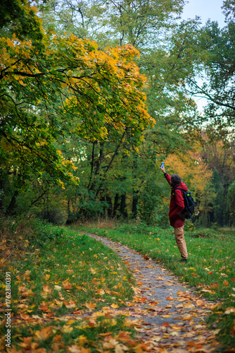 man in red taking a photo of tree branch on mobile phone