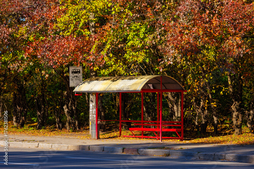 a red bus stop among colorful trees