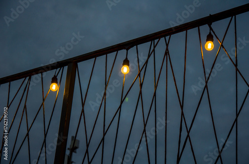 Warm String Lights Hanging on a Diagonal Metal Railing Against a Dark Twilight Sky