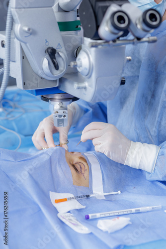 Obraz na plátně Operating microscope with gloved surgeon performing blepharoplasty on a marked e