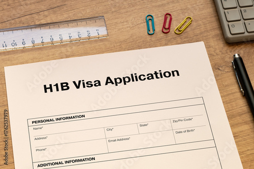 The document of the H1B Visa Application is on the desk, along with a calculator and a pen.