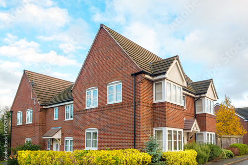 Family houses in UK - Real estate and building concepts in UK. Traditional English red brick houses in new housing development. Street with semi-detached or terraced homes in residential neighbourhood