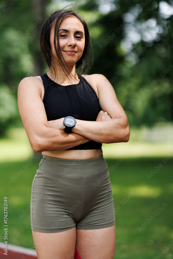 Fototapeta premium Confident Female Athlete Posing Outdoors in Sportswear on a Sunny Day