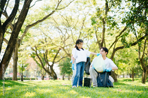 Joyful family volunteering to clean up a green park together. A positive lifestyle scene promoting eco-awareness, teamwork, and love for nature.