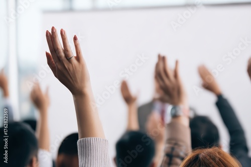 People in an audience raising hands, asking a question, expressing opinion, or showing participation during a business conference