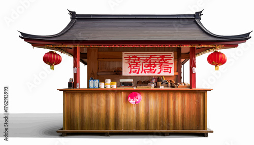 A small, traditional Chinese-style kiosk with a dark roof, red trim, and hanging red lanterns, displaying items for sale behind a bamboo counter.
