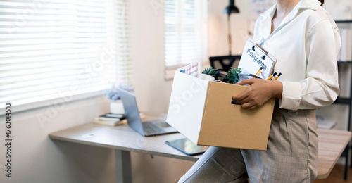 Canvastavla Close-up of an Asian female employee carrying a cardboard box filled with personal items, leaving the office after a layoff or resignation