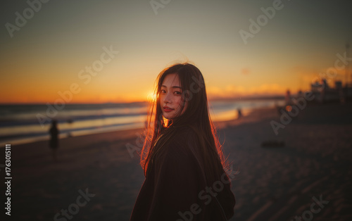 振り向く女性と浜辺の夕陽の風景