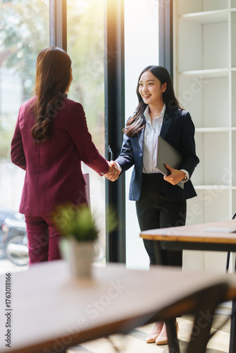 Businesswomen shaking hands after a successful meeting, collaborating and achieving a new agreement in a modern office setup