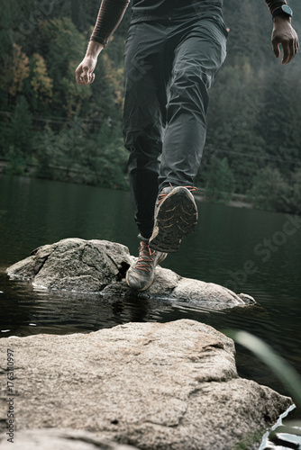 Hiker making a step across the water 