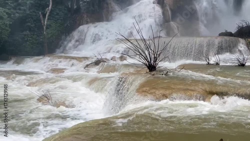 waterfall cascading through lush tropical jungle, surrounded by mist and greenery. The powerful flow of water creates a tranquil and awe-inspiring natural scene in untouched paradise