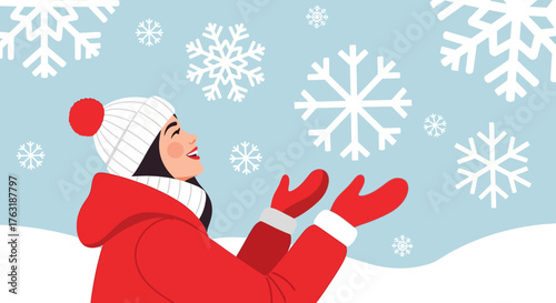Woman in red coat and white hat enjoying the falling snowflakes in winter.