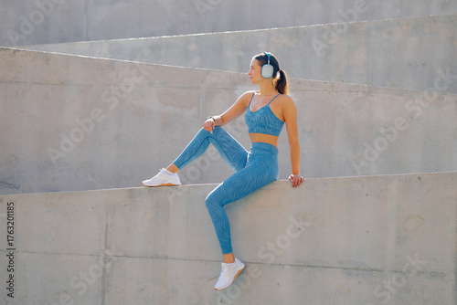 Young woman enjoying outdoor exercise in stylish activewear while listening to music